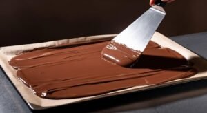 Massa de chocolate fina espalhada em assadeira para rocambole de Bûche de Noël